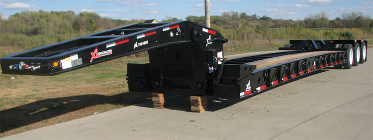 Dropdeck trailer parked on the side of a road 