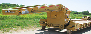 A yellow lowboy trailer parked on the road